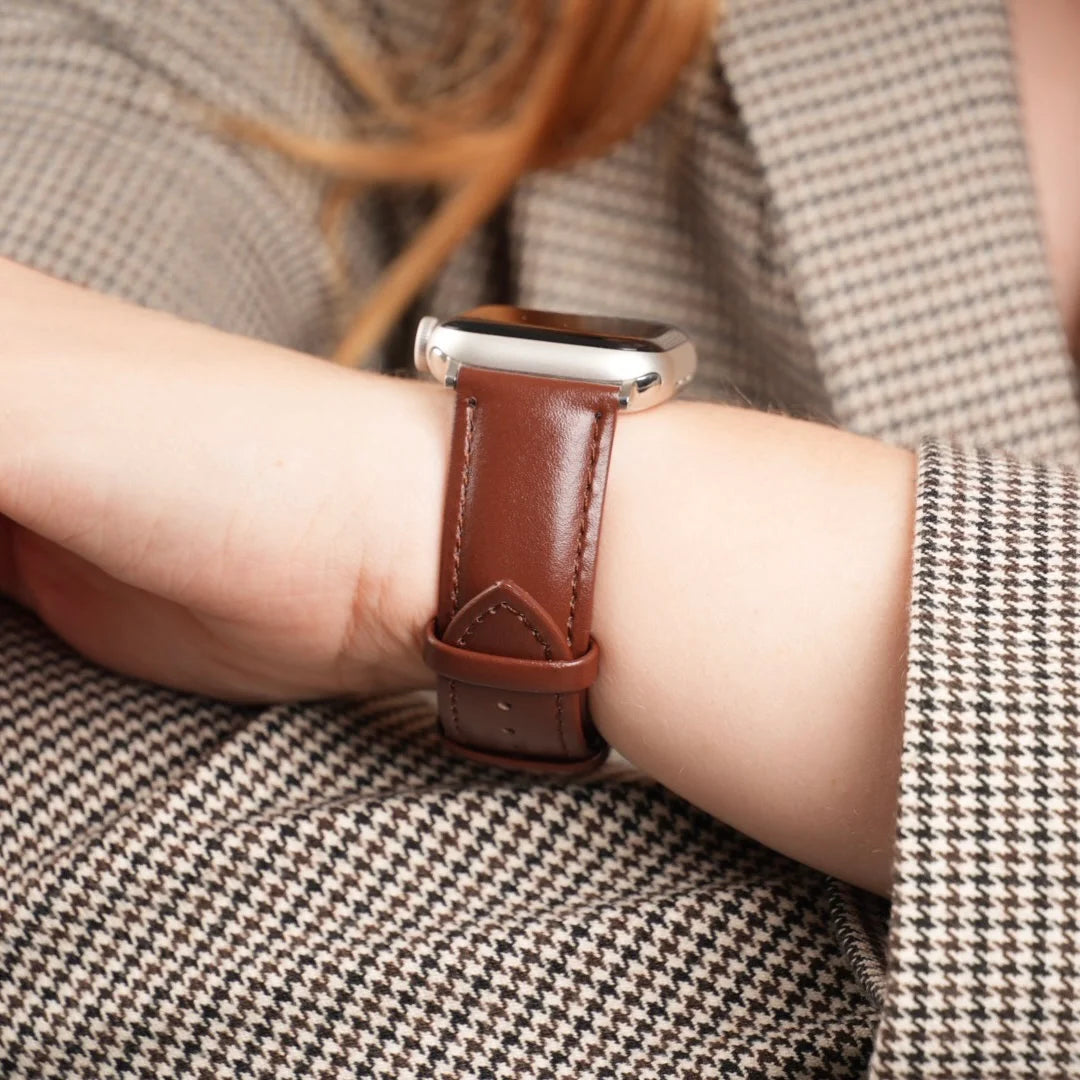 Nahaufnahme des klassischen Breband Lederarmbands in Braun an einer Apple Watch am Handgelenk einer Person im karierten Blazer. #farbe_braun
