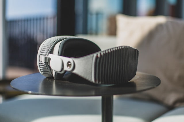 Apple Vision Pro Zubehör: Apple Brille auf rundem Tisch, vor einem Sofa und Fenstern im Hintergrund.