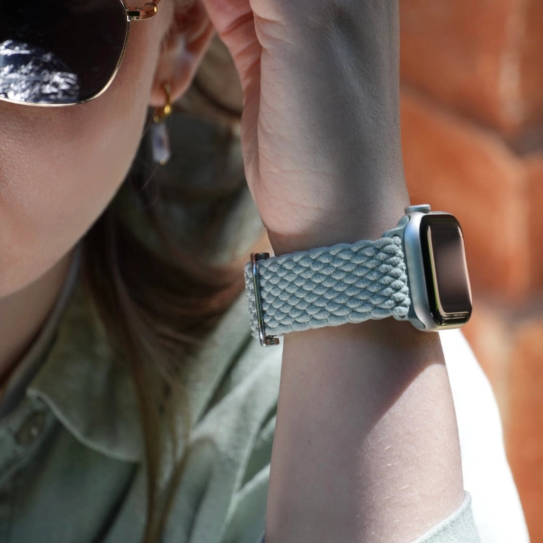 Apple Watch mit gewebtem Nylonarmband in Hellgrün am Handgelenk einer Frau mit Sonnenbrille