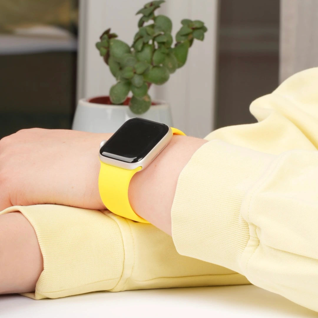 Apple Watch mit gelbem Silikonarmband am Handgelenk #farbe_gelb