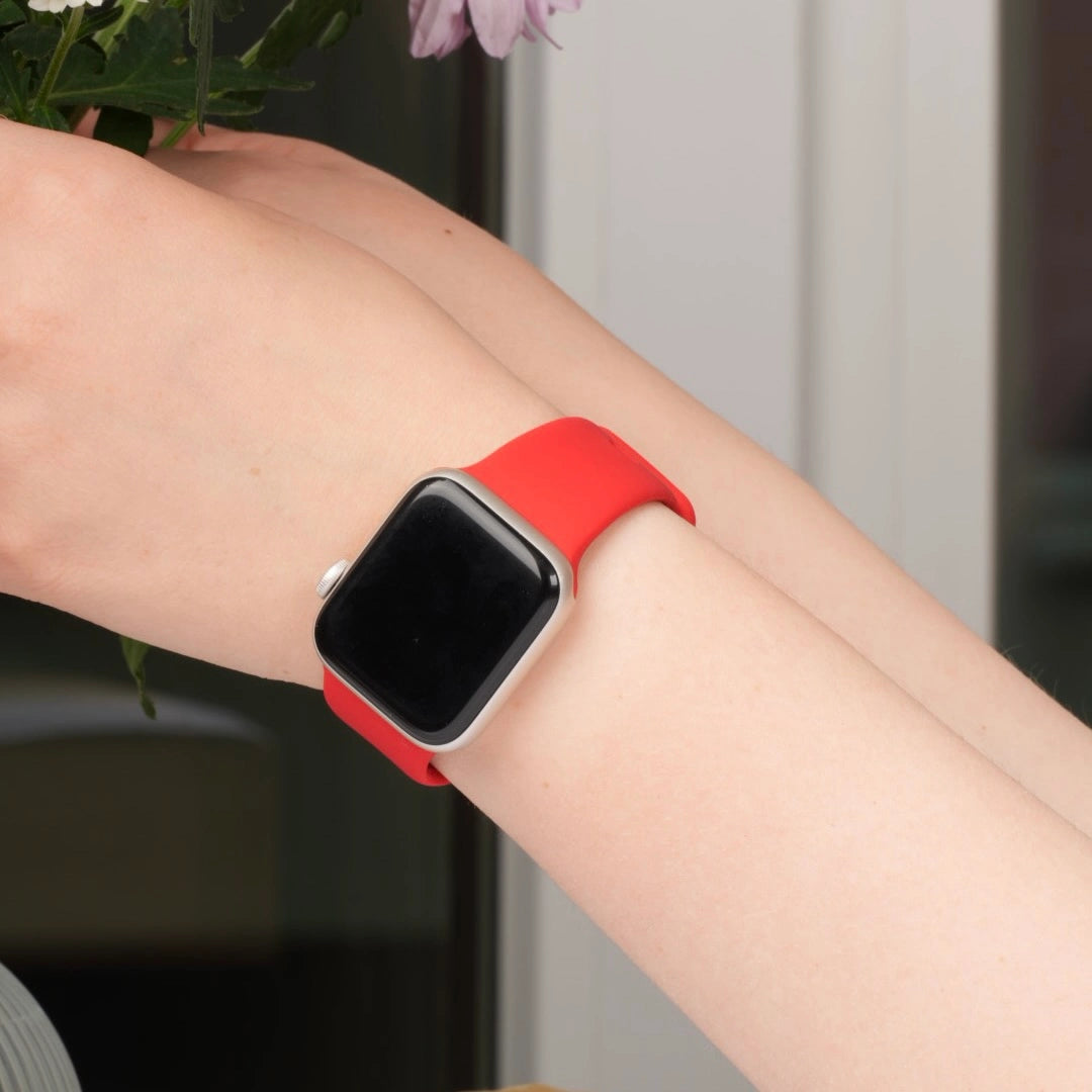 Apple Watch mit rotem Silikonarmband am Handgelenk #farbe_rot